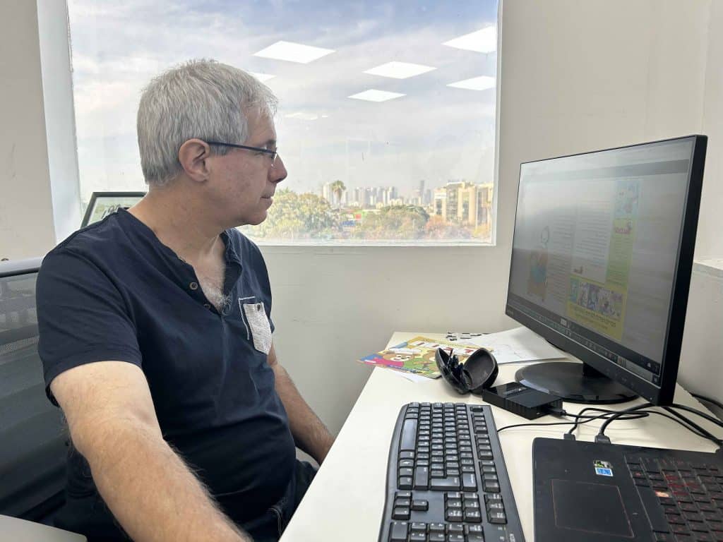 רמי שיר, העורך הראשי והבעלים של הוצאת אצבעוני, מעיין בגיליון של עיתון הילדים "אצבעוני" בספריית המערכת.