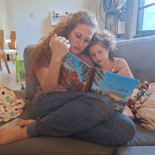 אם יושבת עם שני ילדיה על ספה וקוראת להם מתוך ספר הילדים "ברי בר נשאר ער" – רגע משפחתי מלא חום, אהבה ולמידה משותפת על אהבה ללא תנאי.